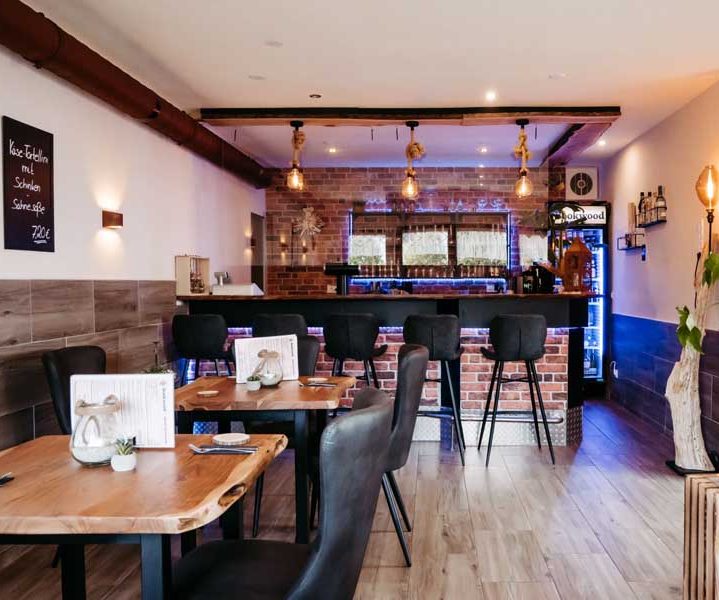 Moderne Café-Atmosphäre mit Holzmobiliar, beleuchteter Bar und stilvollen Tischen.