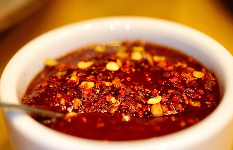 Schüssel mit rotem Chiliöl, dekoriert mit roten Chiliflocken.