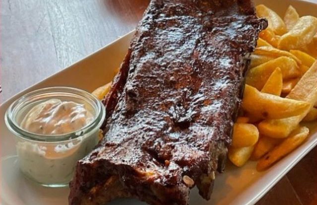 Schweinerippchen mit Pommes und einer Beilage aus Dip in einem Glas.