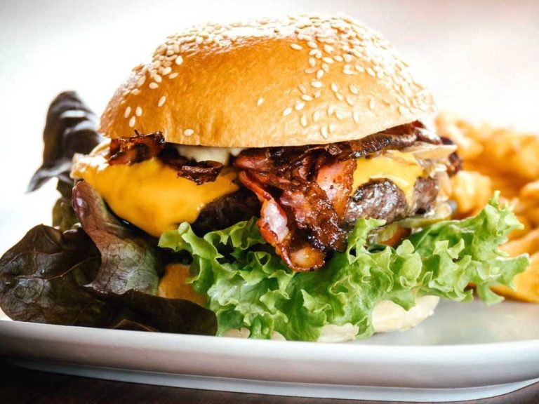 Saftiger Cheeseburger mit Speck, Salat und Käse in einem Sesam-Brötchen.