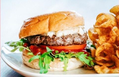Ein saftiger Hamburger mit Salat, Tomate und Zwiebeln, serviert mit Steakhouse Fries.