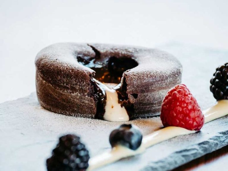 Schoko-Küchlein mit flüssigem Kern, garniert mit Beeren und Sahne.