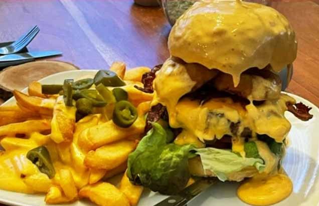 Burger mit extra viel Käse und Käsesoßen-Topping. Serviert mit Pommes frites.