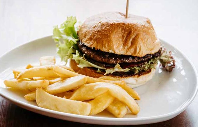 Ein Hamburger mit Salat und Pommes auf einem weißen Teller.
